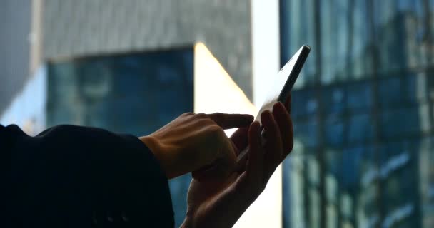 Empresário 4k com telefone móvel ou smartphone perto do prédio de escritórios . — Vídeo de Stock