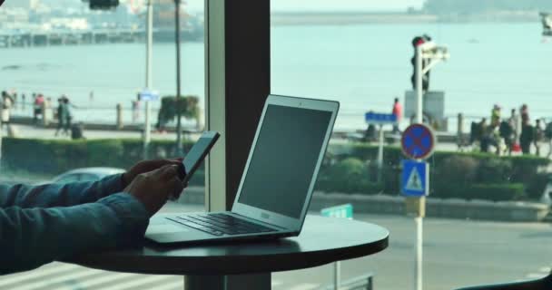 4k female using smartphone,laptop.city pedestrian and traffic window view. — Stock video