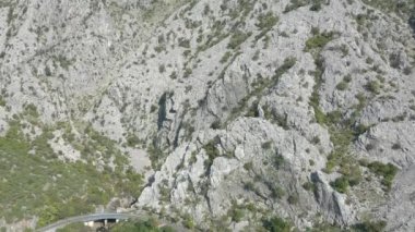 Güneşli bir yaz gününde Karadağ 'ın Boka-Kotor körfezindeki küçük bir yat limanının havadan çekilmiş görüntüleri. Denizin suları zümrüt, arka planda dağlar görünür.