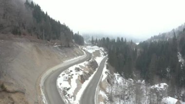 Drone, dağları kaplayan kış ormanının üzerinde yükselir ve uçar, ve arabaların gittiği dar, dolambaçlı dağ yollarında. Köknar ve çam ağaçlarının dalları karla kaplıdır.