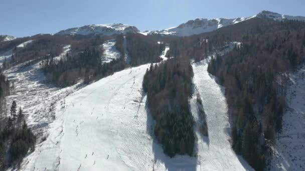 Tournage vidéo aérien d'une station de ski, vue sur la montagne où se trouvent l'ascenseur et la descente, beaucoup de skieurs descendent la montagne 