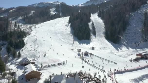 Tournage vidéo aérien d'une station de ski, vue sur la montagne où se trouvent l'ascenseur et la descente, beaucoup de skieurs descendent la montagne 