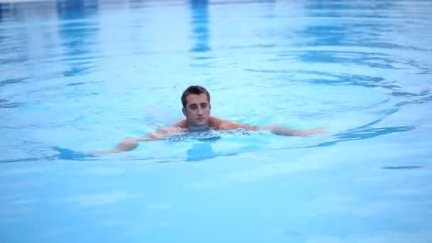 Мускулистый мужчина плавает в бассейне — стоковое видео