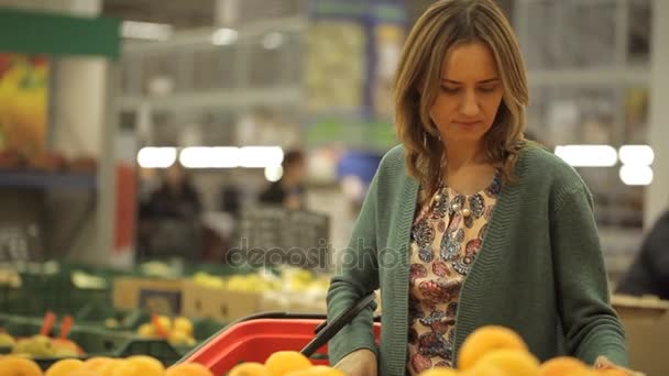 Kvinnan väljer apelsiner på en stormarknad — Stockvideo