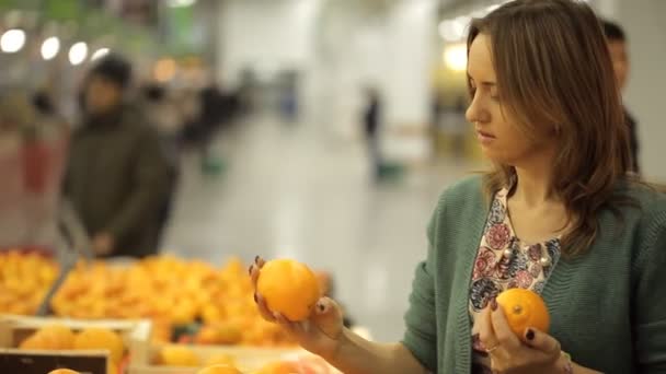 Woman chooses oranges at a supermarket — Stock Video