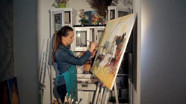 Mladý umělec se štětcem a barvami maluje obraz — Stock video