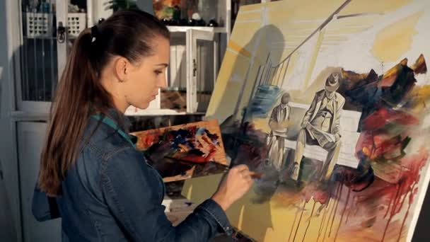 Ένας νεαρός καλλιτέχνης με ένα πινέλο και τα χρώματα ζωγραφίζει μια ζωηρή εικόνα — Αρχείο Βίντεο