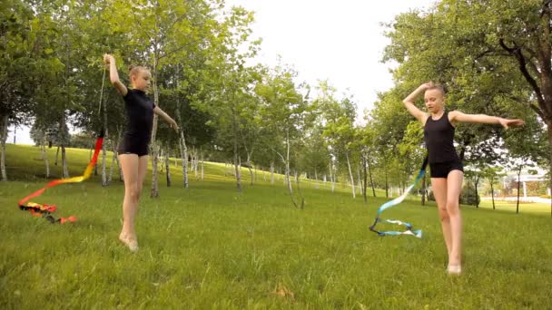 Las niñas participan en la gimnasia rítmica con cinta en la naturaleza — Vídeos de Stock