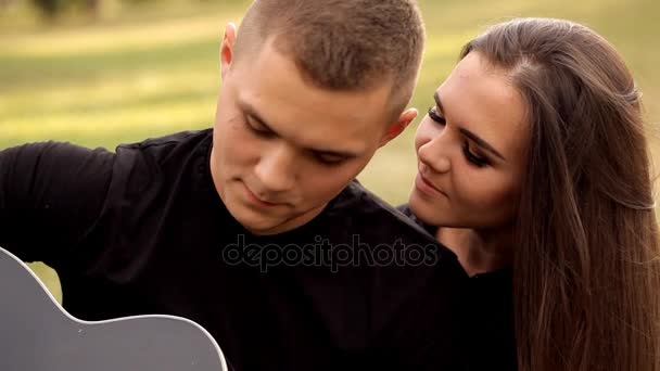 Jovem romântico na natureza toca sua namorada na guitarra — Vídeo de Stock