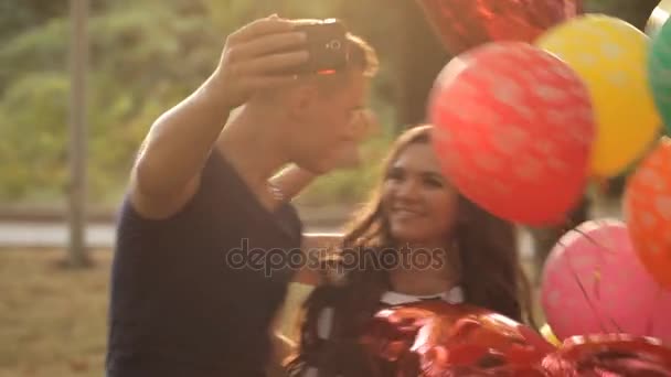 Νεαρό ζευγάρι κάνει selfie με μπαλόνια σε ένα πάρκο αναψυχής — Αρχείο Βίντεο