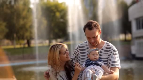 Молода сім'я з дитиною, що йде біля фонтану — стокове відео