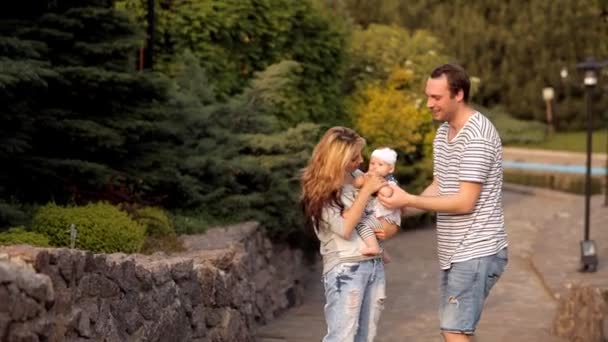 Familia joven con un niño pasea por el soleado Parque — Vídeos de Stock