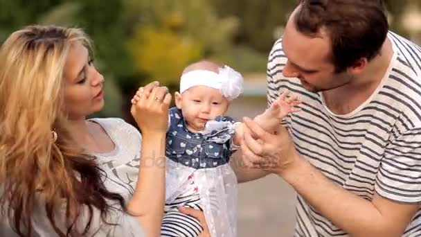 Молодые родители в парке показывают любовь к своему ребенку — стоковое видео