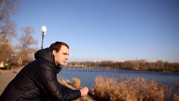 Jeune homme pensif debout sur le quai et regardant le lac — Video