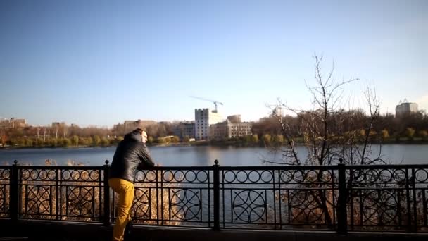 Jeune homme pensif debout sur le quai et regardant le lac — Video