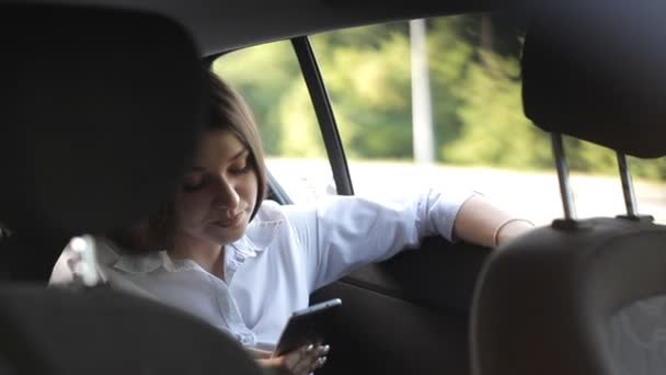 Meravigliosa ragazza d'affari cavalca in un taxi e di utilizzare il telefono — Video Stock