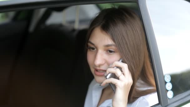 Prachtig bedrijf meisje rijdt in een taxi en praten over de telefoon — Stockvideo