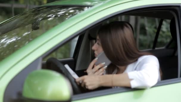 Lány egy kocsiban beszél a telefonon a dolgára, és megjegyzi, hogy a notebook — Stock videók