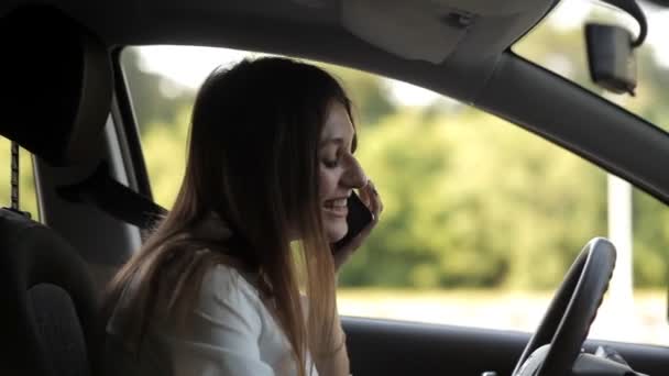 Leuk meisje praten aan de telefoon achter het stuur van de auto — Stockvideo