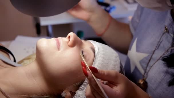 Der Maskenbildner entfernt dem Kunden alte Wimpern, bevor er neue aufbaut — Stockvideo