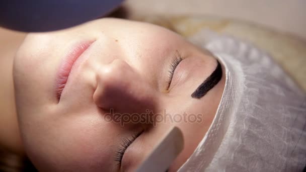 Dans le salon de beauté, le maquilleur prépare la jeune fille à la procédure d'extension des cils. Gros plan — Video