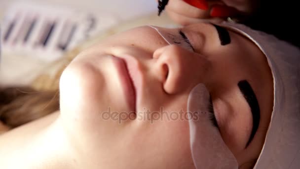 No salão de beleza, o maquiador prepara a menina para o procedimento de extensão de pestanas. Close-up — Vídeo de Stock