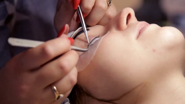 I skönhetssalongen ökar make-up artist ögonfransar till flickan. Närbild — Stockvideo