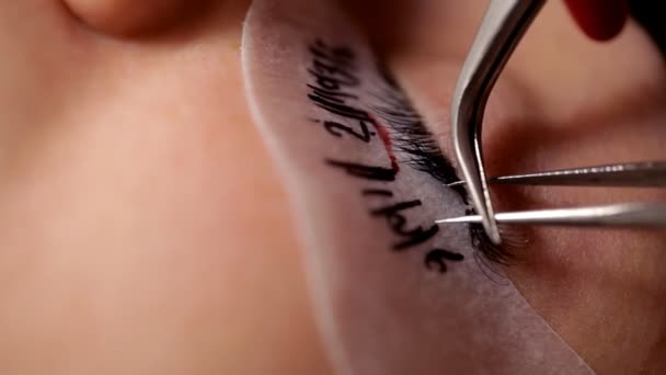 Im Schönheitssalon vergrößert die Visagistin dem Mädchen die Wimpern. Nahaufnahme — Stockvideo