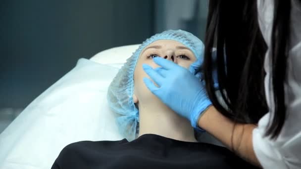 No salão de beleza o médico-cosmetologist prepara a menina para o procedimento de aumento de lábios — Vídeo de Stock