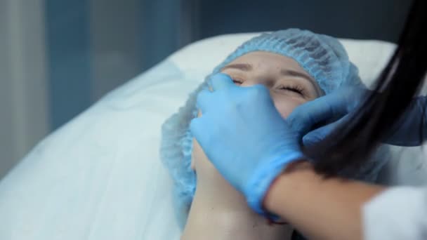 Den läkare-kosmetolog smörjer lösningen av flickor läpparna innan förfarandet att öka läpparna. Botox injektion — Stockvideo