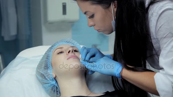 In the beauty salon the doctor-cosmetologist injects Botox into the girls lips. The process of lip augmentation — Stock Video