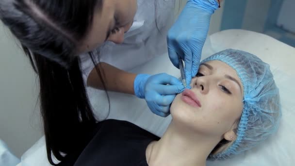 Doktor kosmetička je mladá dívka lip rozšíření postupy. Botox injekce v klinice. — Stock video