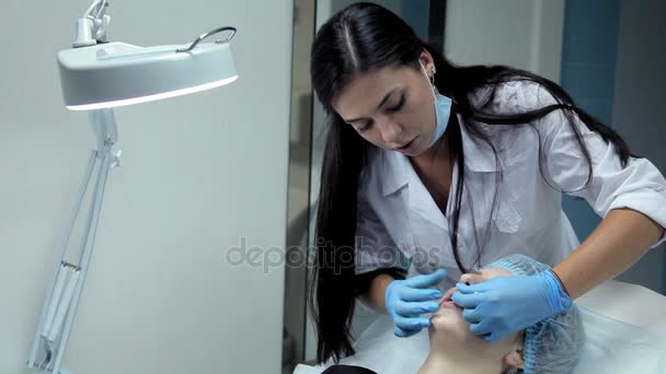 El esteticista suaviza el botox en los labios de una niña después de la inyección. Procedimiento de aumento de labios . — Vídeos de Stock