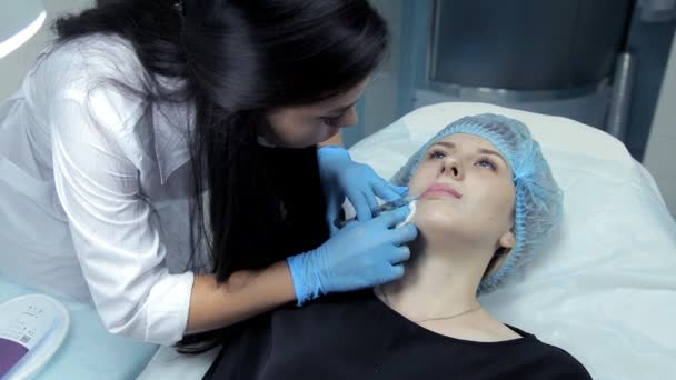 El médico-cosmetólogo introduce Botox en los labios de las niñas para agrandarlos. Aumento de labios en la clínica — Vídeos de Stock