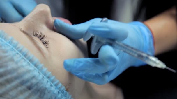 Косметолог разглаживает ботокс в губах молодой девушки после инъекции. Увеличение губ . — стоковое видео