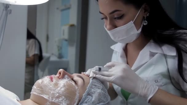 Nel salone di bellezza, il cosmetologo inietta la ragazza nel viso con lo scopo di ringiovanimento della pelle. — Video Stock