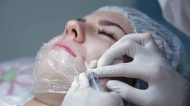 In the beauty salon, the cosmetologist physician injects hyaluronic acid into the face. The procedure of biorevitalization — Stock Video