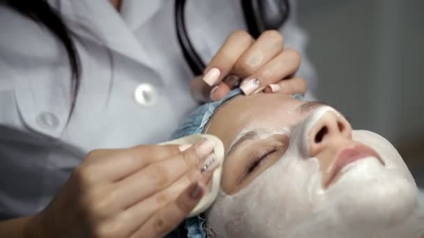 The beautician removes the mask from the face of the girl — Stock Video