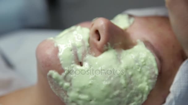 In the beauty salon beautician imposes on a clients face algae mask after the procedure of cleaning the face — Stock Video