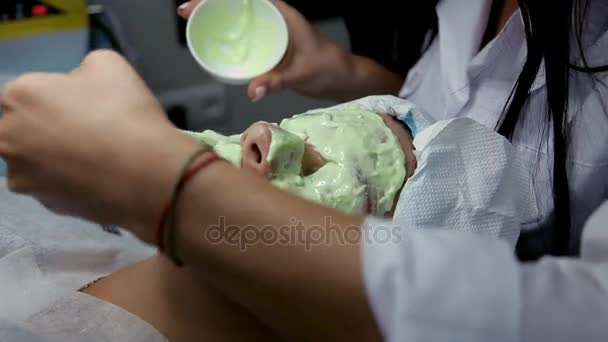 In de schoonheidssalon oplegt schoonheidsspecialiste een klanten gezichtsmasker algen na de procedure voor het reinigen van het gezicht — Stockvideo