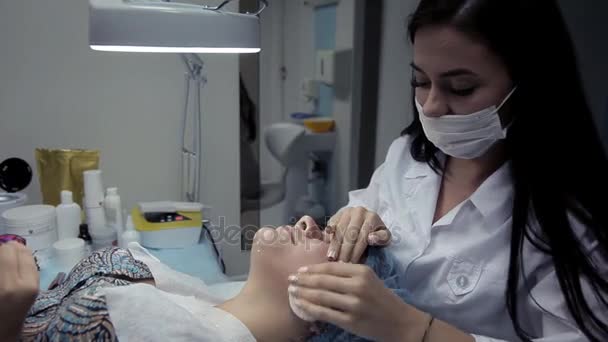 Салон краси косметолог видаляє залишки альгінатної маски з обличчя клієнта — стокове відео