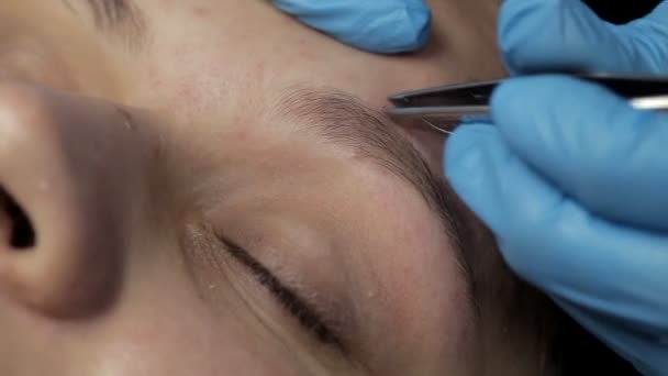 Cosmetologist faz a correção da sobrancelha ao cliente — Vídeo de Stock