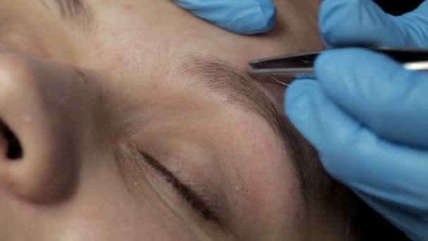 Cosmetólogo hace corrección de cejas al cliente — Vídeo de stock