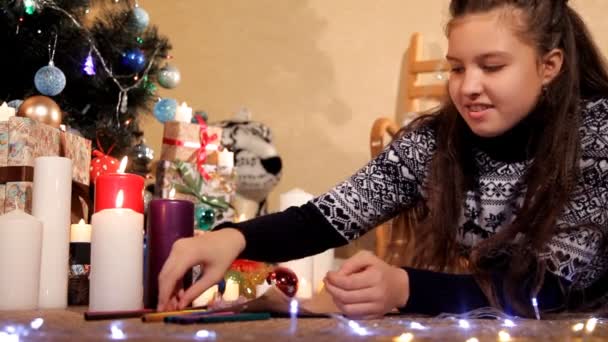 Een klein meisje in een feestelijke omgeving schrijft een brief aan de kerstman met haar wensen voor het nieuwe jaar — Stockvideo