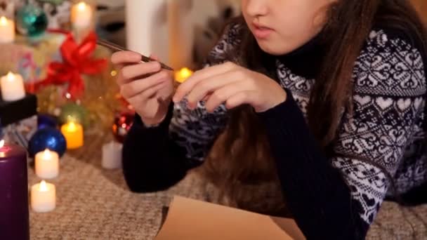 Petite fille dans un cadre festif sur une feuille de papier dessine une carte de Noël Père Noël — Video