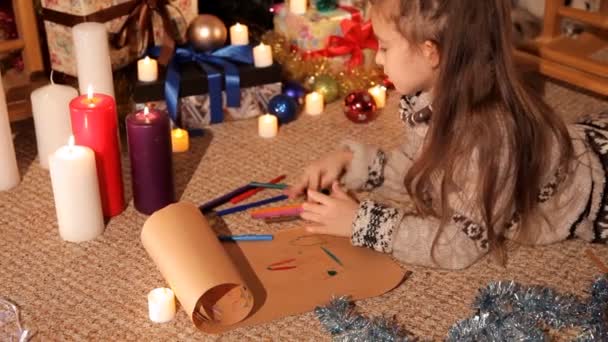 Une petite fille écrit et dessine au Père Noël une lettre de Noël sur ses souhaits pour la nouvelle année — Video