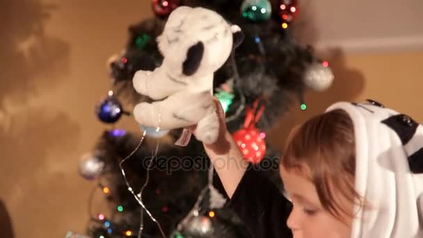 Child opens a New Years gift near a Christmas tree — Stock Video