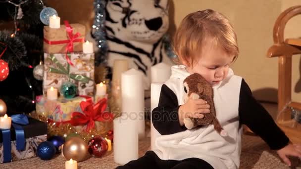 Menina está jogando perto de uma árvore de Natal com um presente de Ano Novo — Vídeo de Stock