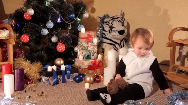 Niña está jugando cerca de un árbol de Navidad con un regalo de Año Nuevo — Vídeo de stock