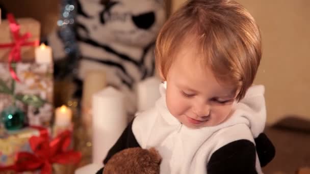 Kleines Mädchen spielt in der Nähe eines Weihnachtsbaums mit einem Neujahrsgeschenk — Stockvideo